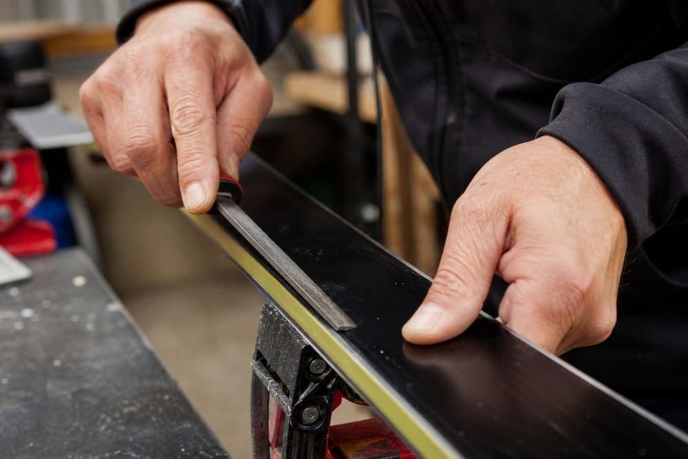 Filing a steel ski edge on the bench
